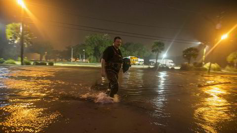 En mann vader igjennom en oversvømt strandvei idet sentrum av orkanen Nate nærmer seg Biloxi i Mississippi.