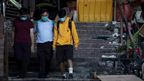 En rektor følger to ungdommer ut fra Hongkongs tekniske universitet. Om lag hundre demonstranter skal være igjen inne på området. Foto: Ng Han Guan / AP / NTB scanpix