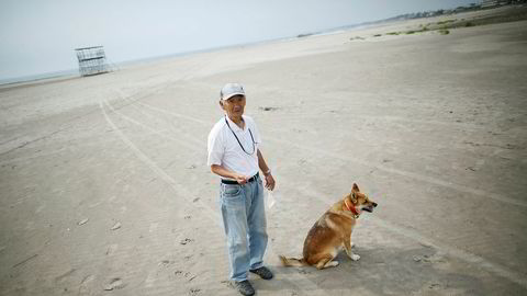 Forskere har målt høye nivåer av radioaktiv stråling på strender langt fra det ødelagte kjernekraftverket i Fukushima. På bildet ser vi lokal beboer Takeshi Takaki ( 71) og hans hund Marron på den tomme stranden Yotsukura 40 kilometer fra Fukushima. Denne stranden er ikke undersøkt av forskerne.