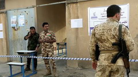 Kurdiske peshmerga-krigere holder vakt utenfor et stemmelokale under den omstridte avstemningen om kurdisk uavhengighet fra Irak.