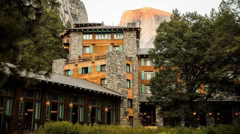 Träd, gres och stenar. Majestic Yosemite Hotel ser nesten ut som en del av naturen, der det ruver i nasjonalparken. I aftensolen skimtes fjelltoppen Half Dome, der man kan klamre seg opp i kø om klatretillatelsen er på plass.