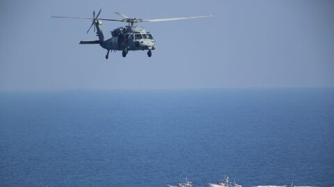 På dette arkivbildet ses et amerikansk MH-60 Seahawk-helikopter som sirkler over patruljebåter fra Irans revolusjonsgarde i Hormuzstredet.