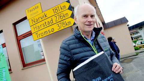 Svein Arnt Uhre, leder for aksjonsgruppen for Nord-Norgebanen, står foran skilt som viser hva avstandene fra Fauske til Narvik, Harstad og Tromsø vil bli med tog.