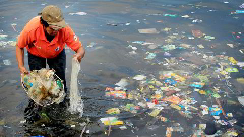 I mange asiatiske land har det hopet seg opp store plastfjell på mange deler av kysten. Bildet viser en hjelpearbeider som samler plastavfall på en strand nær Manila på Filippinene.
