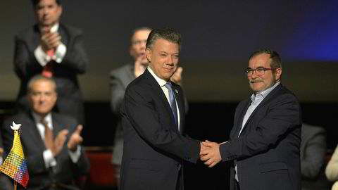 Colombias president Juan Manuel Santos (til venster) og leder av Farc-gerilliaen Timoleon Jimenez, også kjent som Timochenko, håndhilser etter den historiske fredsavtalen.