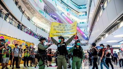 Opprørspoliti inne på et kjøpesenter i Hong Kong mandag denne uken holder opp en plakat som advarer demonstranter om at de kan bli straffeforfulgt.