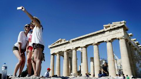 En gruppe turister tar en selfie foran Parthenon-tempelet på toppen av Akropolis i Aten. Hellas er ett av landene hvor man kan bruke mobilen som hjemme i sommer. Men det er fortsatt lurt å følge med på databruken i ferien.