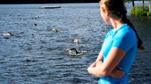 Svømmetrener Emma Augustsson ser ut over Sognsvann og triatletene som svømmer mot henne.