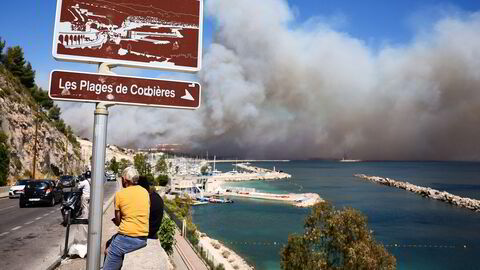 Folk ser på fra veikanten mens skogbranner truer Marseille i Frankrike. Slike ekstremværhendelser kan true økonomien, skriver Espen Swartling.