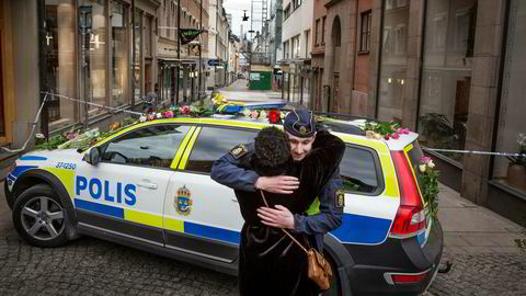 Drottninggatan i Stockholm er Sveriges travleste handlegate der fire mennesker døde fredag. Her får en politimann blomster og en klem av en forbipasserende.