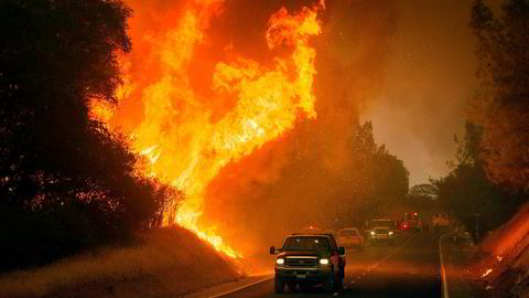Biler kjører forbi flammene til «ildveggen» i California lørdag. Det var mange branner i delstaten etter en rekordsettende hetebølge.