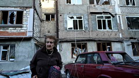 En eldre kvinne bærer sine eiendeler vekk fra leilighetskomplekset som er hardt rammet av kampene i byen Stepanakert i Nagorno-Karabakh.