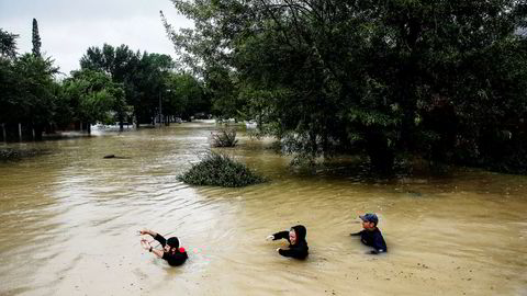 Tre mennesker vasser i det høye vannet ned en gate i Houston i Texas. Orkanene Harvey har forårsaket kontinuerlig regn de siste dagene.