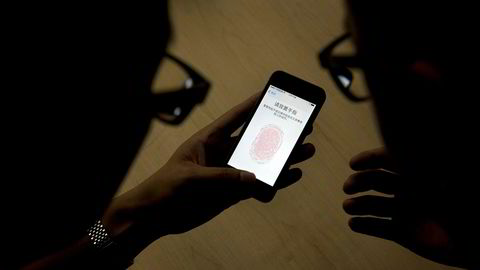 Illustrasjonsbilde. En ansatt viser frem fingerskanneren på en iPhone 5s. Nå ønsker politiet å kunne bruke tvang for å få åpnet telefoner som antas å inneholde bevis.