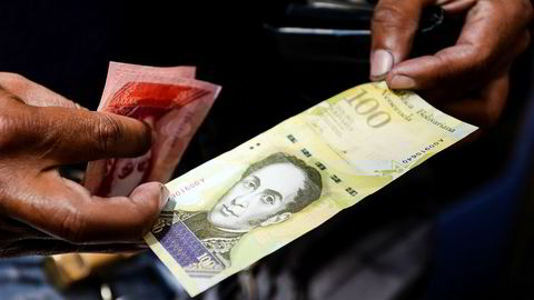 Venezuela vil trolig havne i mislighold av landets enorme statsgjeld. På bildet viser en mann frem landets nye 100.000-Bolivar-seddel. i det offisielle markedet er den verdt 29,89 dollar, men på svartebørs kan man kjøpe den for to dollar.