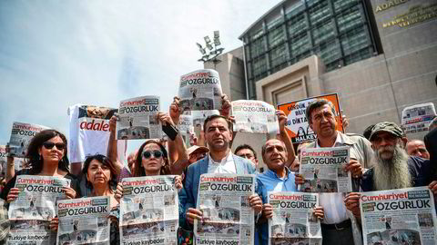 Folk holder opp dagens utgave av Cumhuriyet i protest, fredag 28. juli, utenfor domstolen der saken mot journalister fra avisen føres.